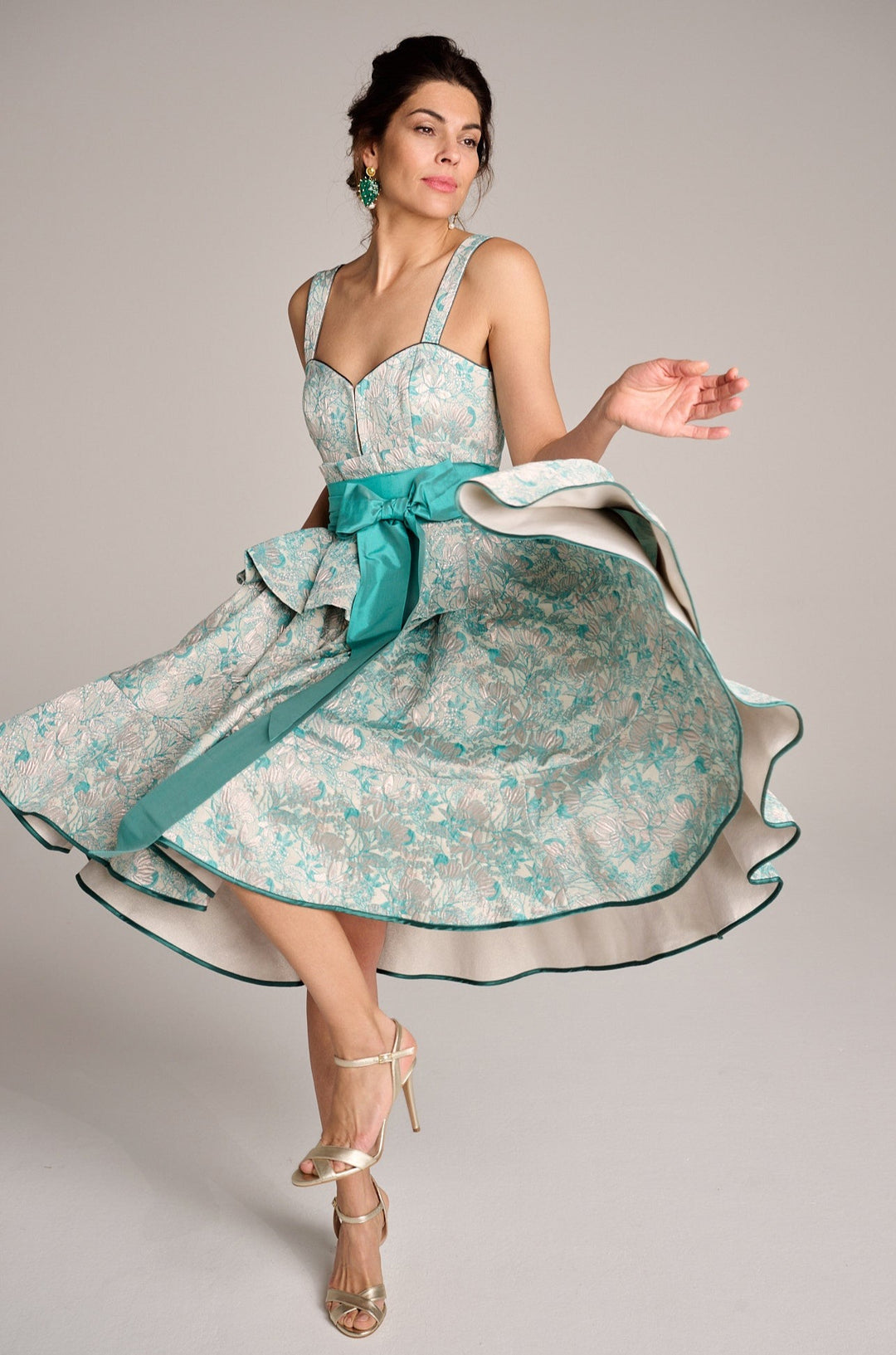 Ein folkloreartiges Dindl Kleid in Candyfarbenem Türkis von einer schönen Frau tänzerisch hochschwingend getragen. Das außergewöhnlich weibliche Dirndl hat keine Schürze und wird dank des herzförmigen Ausschnittes ohne Bluse gewählt 